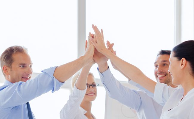 happy business team giving high five in office